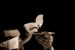 Hands of priest holding up the Eucharist